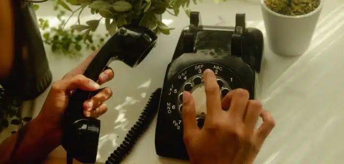 person holding black rotary telephone