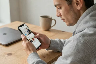 Jeune homme naviguant sur un site web depuis son smartphone Android à son bureau à domicile