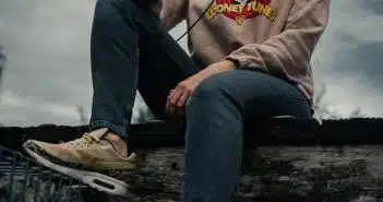 woman in gray hoodie and blue denim jeans sitting on wooden bench